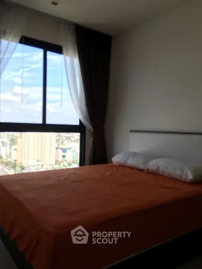 Cozy bedroom with city view and large window, perfect for urban living.