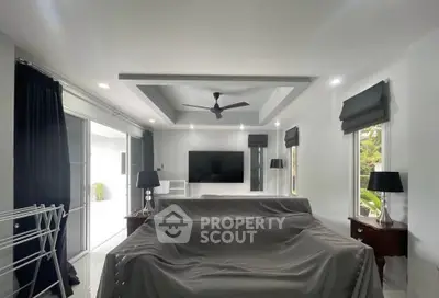 Spacious living room with modern ceiling design and large TV, perfect for entertainment.