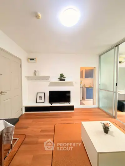 Modern living room with sleek design and wooden flooring, featuring a TV and stylish decor.