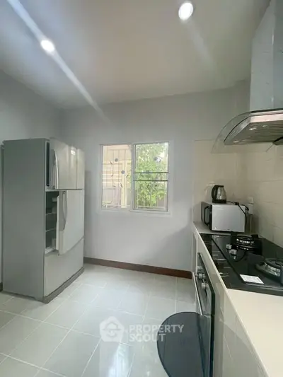 Modern kitchen with gas stove and stainless steel fridge in bright interior