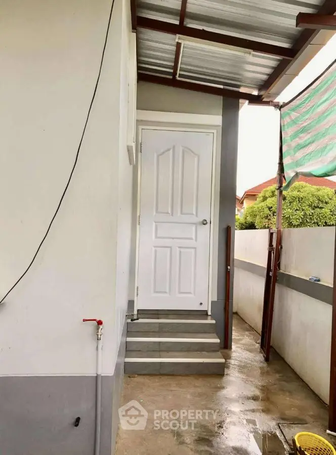 Charming side entrance with covered porch and steps leading to a white door.