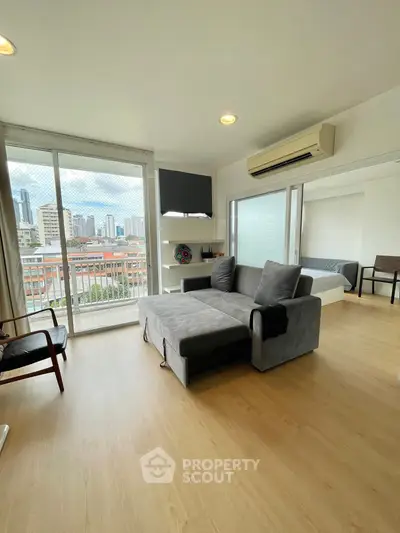 Modern living room with city view, featuring sleek furniture and large windows for natural light.