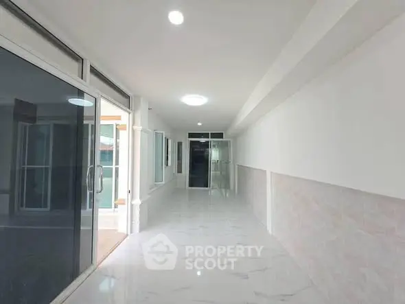Spacious modern corridor with sleek marble flooring and glass doors, ideal for contemporary living.