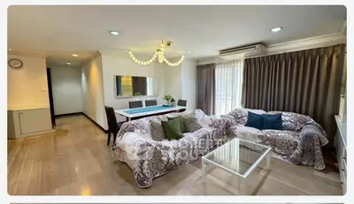 Spacious living room with elegant decor and ample natural light, featuring comfortable seating and a stylish dining area.