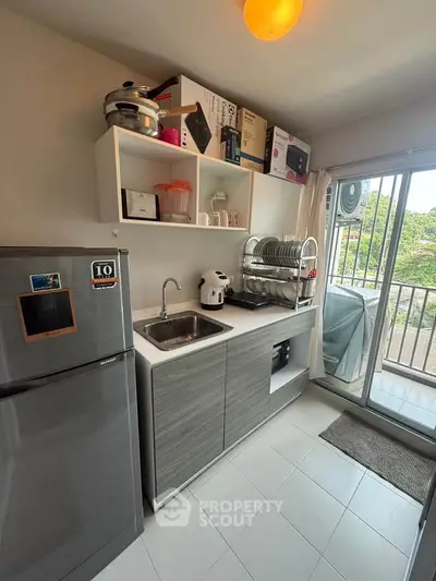 Modern kitchen with sleek cabinetry and balcony view, featuring compact appliances and ample storage space.