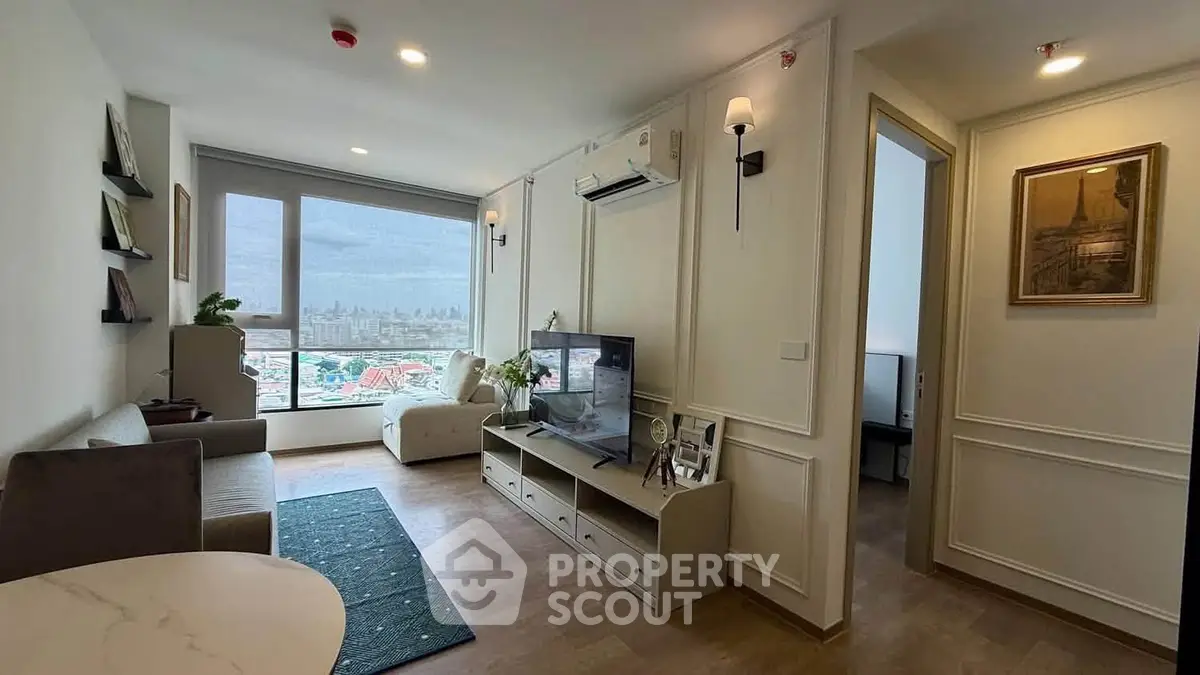 Modern living room with city view, stylish decor, and ample natural light in a high-rise apartment.
