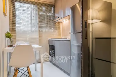 Modern kitchen with sleek design, featuring a compact dining area and large window blinds.