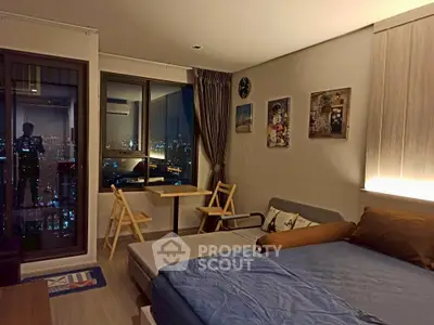 Modern studio apartment with city view, cozy furnishings, and ambient lighting.