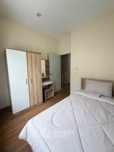 Cozy bedroom with modern furniture and wooden flooring, perfect for a serene living experience.