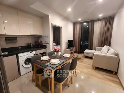 Modern open-plan living room and kitchen with elegant dining area and cozy seating.