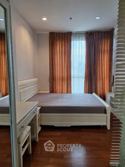 Cozy bedroom with wooden flooring and elegant curtains in a modern apartment.
