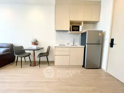 Modern studio apartment with compact kitchen and dining area, featuring sleek appliances and stylish furniture.