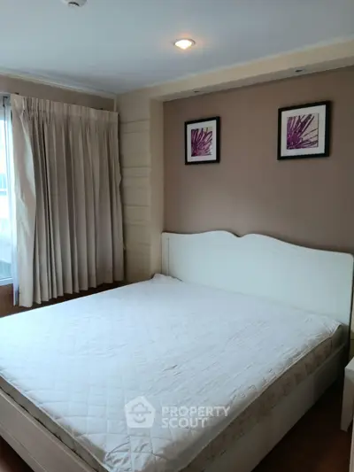 Cozy bedroom with elegant decor and natural light, featuring a comfortable bed and stylish artwork.