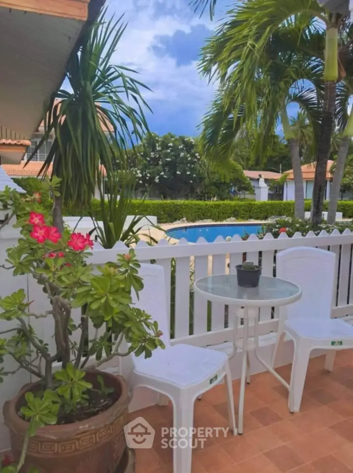 Charming garden patio with pool view and tropical plants, perfect for relaxation.