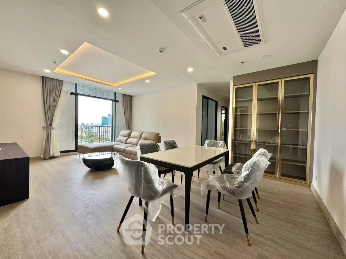 Spacious modern living room with dining area and large windows offering city views.
