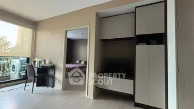 Modern apartment interior with bedroom view and balcony access, featuring sleek storage and workspace.