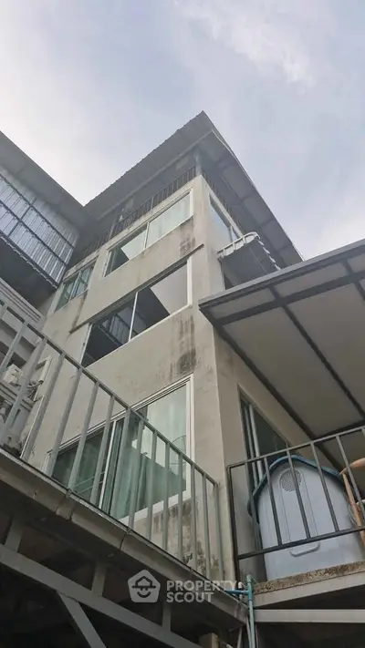 Modern multi-story building with large windows and balconies, showcasing urban architecture.