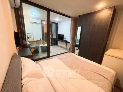 Modern bedroom with glass partition and cozy living area in a stylish apartment.