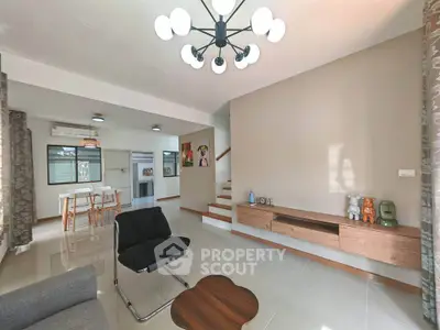 Modern living room with stylish furniture and open dining area, featuring contemporary lighting and neutral tones.