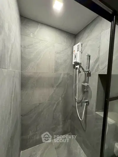 Modern bathroom with sleek gray tiles and a contemporary shower setup.