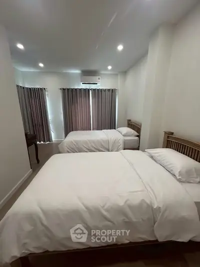 Spacious bedroom with twin beds and modern decor in a cozy apartment.