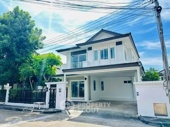 Charming two-story white house with spacious driveway and lush greenery