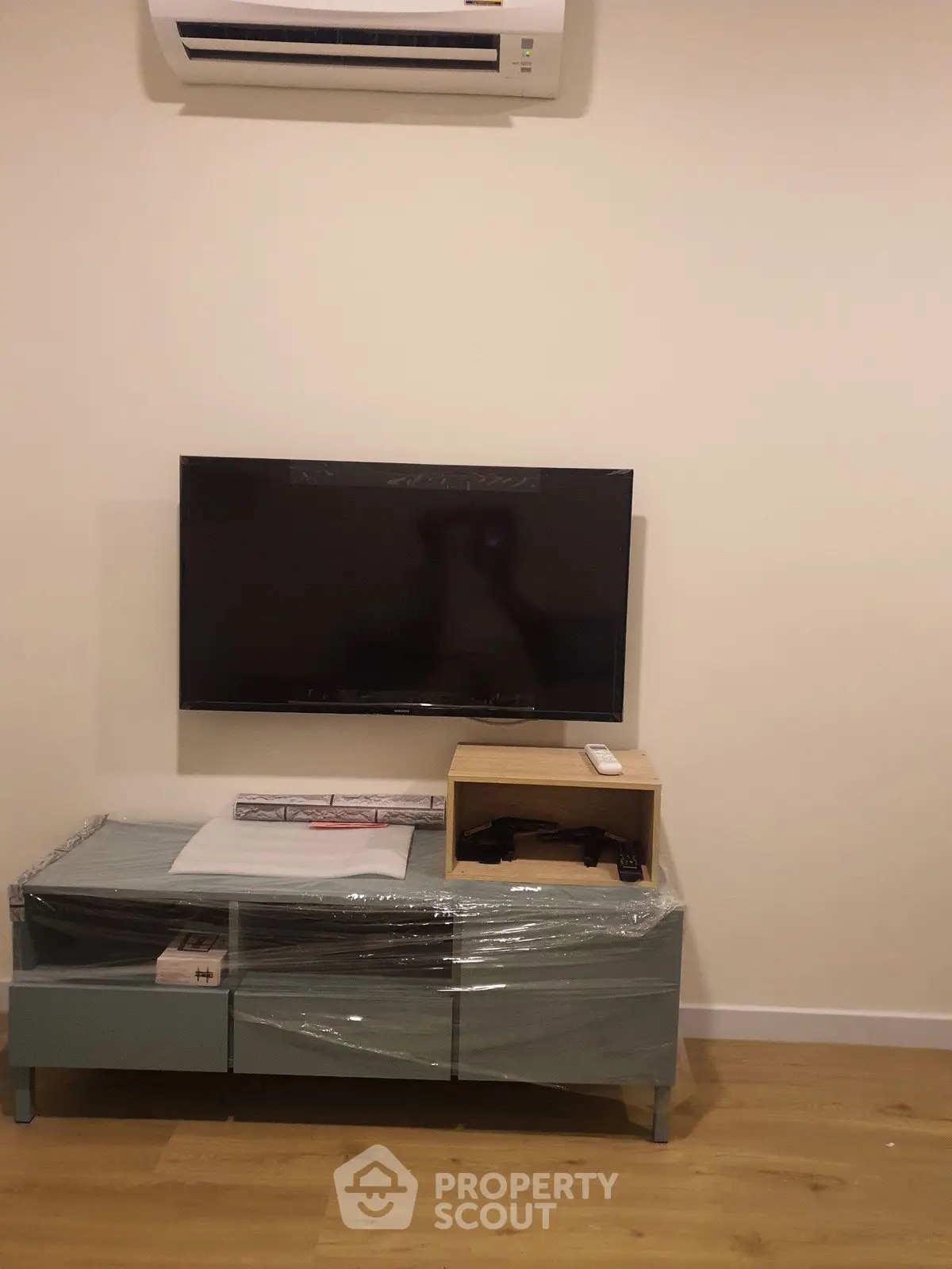 Modern living room with wall-mounted TV and air conditioning unit, featuring sleek furniture.