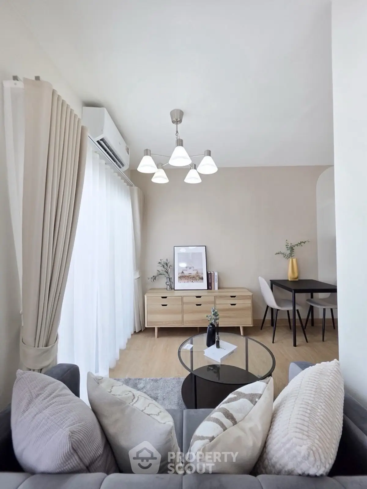 Modern living room with elegant decor and natural light, featuring a cozy sofa and stylish dining area.