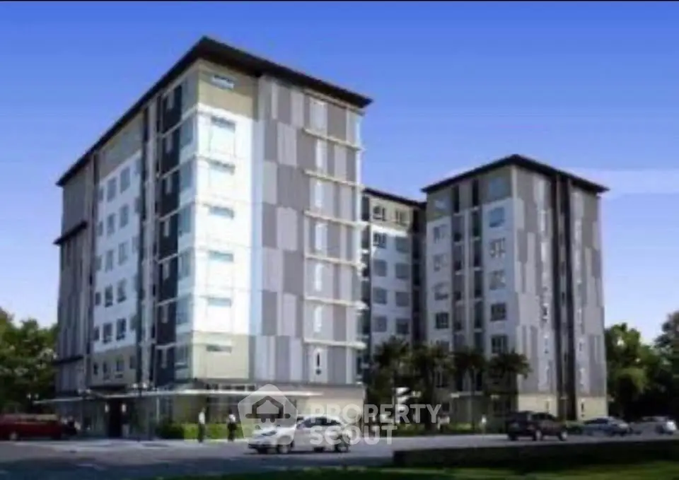 Modern multi-story apartment building with sleek design and ample parking space.
