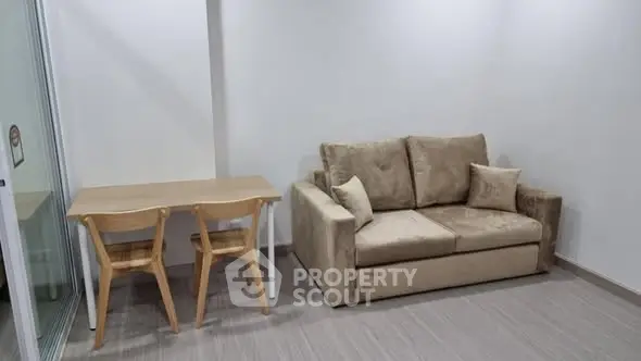 Cozy living room with beige sofa and wooden dining set in modern apartment.