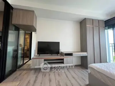 Modern bedroom with sleek built-in furniture and large TV, featuring a minimalist design and natural light.