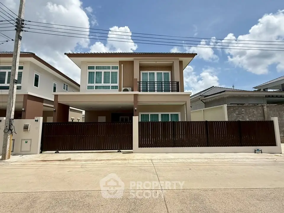 Modern two-story house with balcony and gated entrance in a suburban neighborhood.