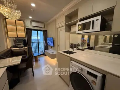 Luxurious modern living room with open kitchen, featuring elegant chandelier and balcony view.