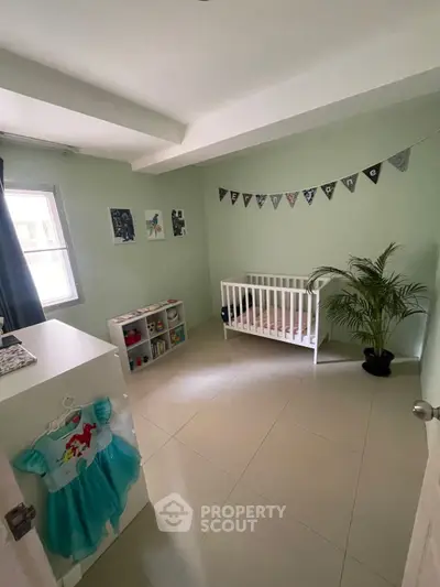 Charming nursery room with crib, soft green walls, and natural light, perfect for a cozy family home.