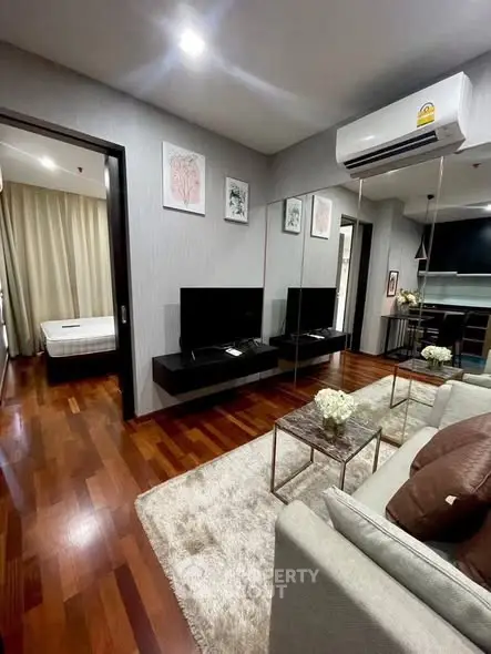 Modern living room with hardwood floors, cozy sofa, and wall-mounted TV in stylish apartment.