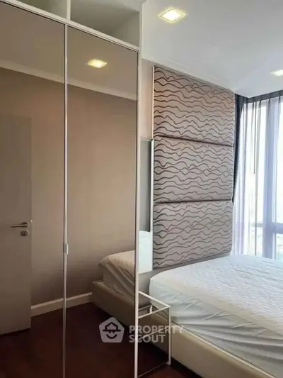 Modern bedroom with stylish decor and mirrored wardrobe, offering a cozy and elegant living space.