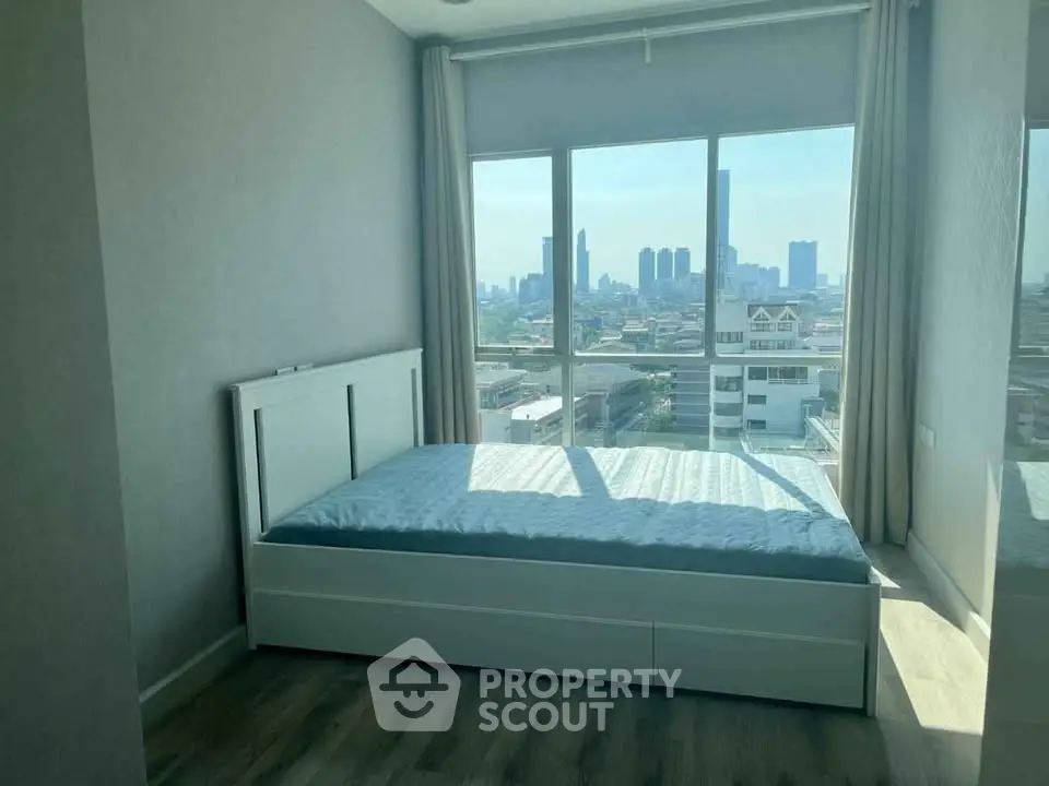 Modern bedroom with city view and large windows in a high-rise apartment.