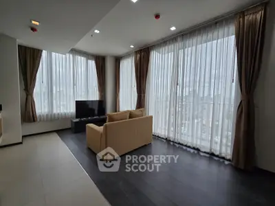 Spacious modern living room with large windows and city view, featuring elegant curtains and a cozy sofa.