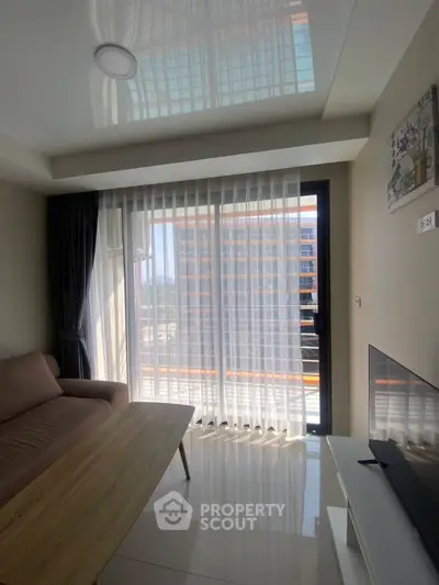 Modern living room with floor-to-ceiling windows and a cozy sofa, offering a bright and inviting atmosphere.