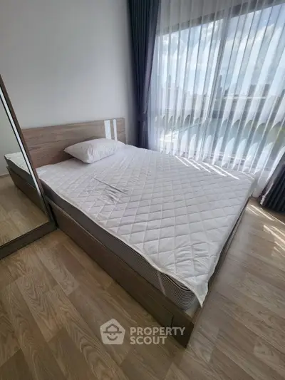 Modern bedroom with large window and wooden flooring, featuring a comfortable bed and mirrored wardrobe.