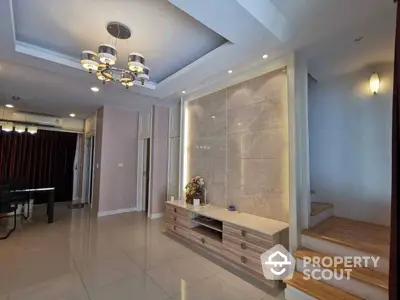 Spacious and elegant living room with polished tile flooring, modern lighting fixtures, and a sophisticated neutral color palette.