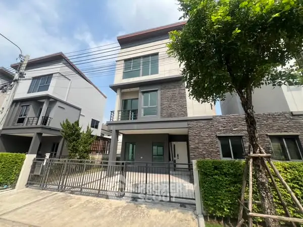 Modern three-story townhouse with gated driveway and lush greenery.