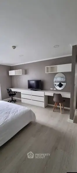 Modern bedroom with sleek furniture and workspace, ideal for comfort and productivity.