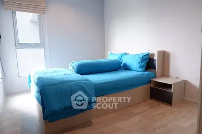 Cozy bedroom with modern wooden flooring and bright blue bedding, perfect for a restful retreat.