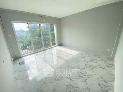 Spacious empty room with large windows and marble flooring, offering a bright and airy atmosphere.