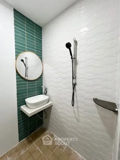 Modern bathroom with stylish green and white tiles, round mirror, and sleek shower design.