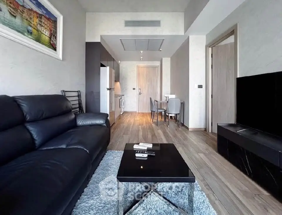 Modern living room with sleek black furniture and open kitchen layout