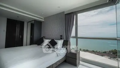 Luxurious bedroom with stunning ocean view from large window, modern decor and elegant furnishings.