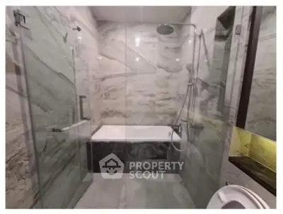 Luxurious bathroom with marble walls and glass shower enclosure