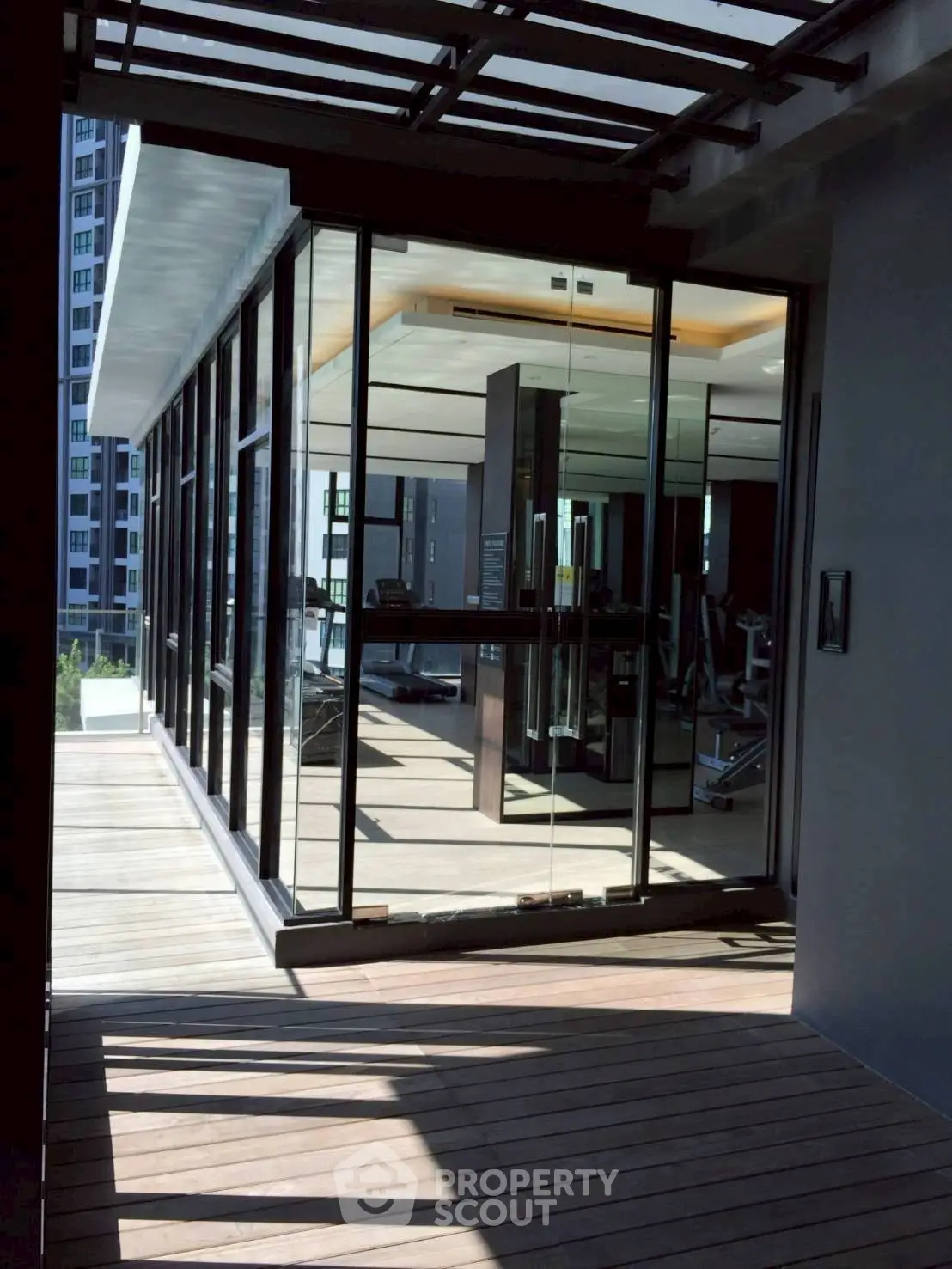 Modern gym with glass walls and wooden deck in luxury building